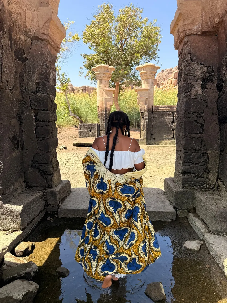 A woman standing in an ancient temple doorway among weathered stone walls on Heissa Island