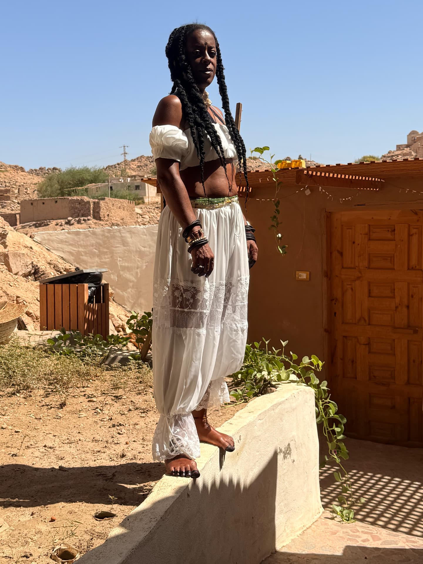 Dhyani Love in white lace at the sanctuary, the Nubian village and hills of Heissa Island behind her