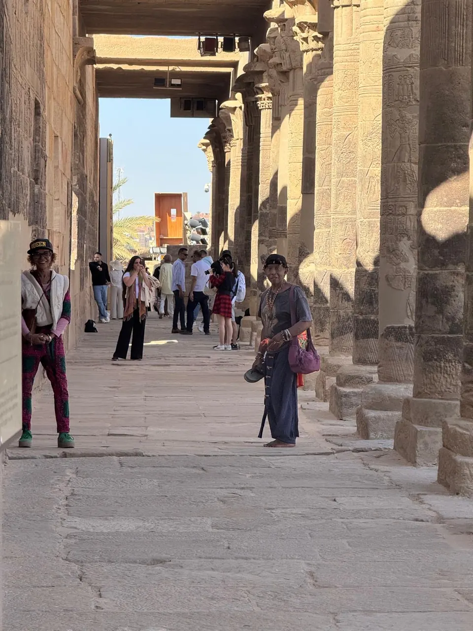 People walking between ancient sandstone columns at the Temple of Auset
