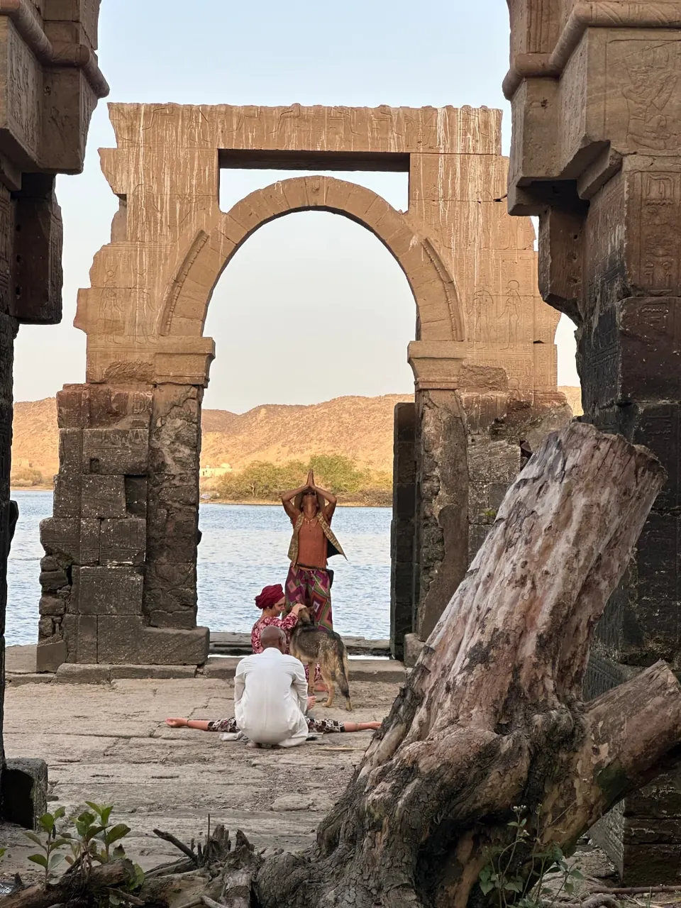 Beneath a weathered stone archway overlooking the Nile, with traditional boats on the water, Heissa Island